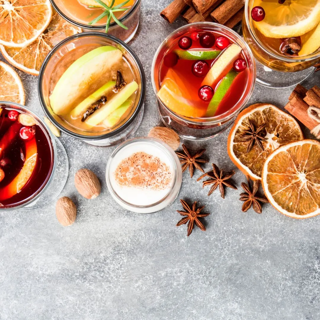 Verschiedene Gewürze wie Zimtstangen, Sternanis und getrocknete Orangen auf einem Holztisch