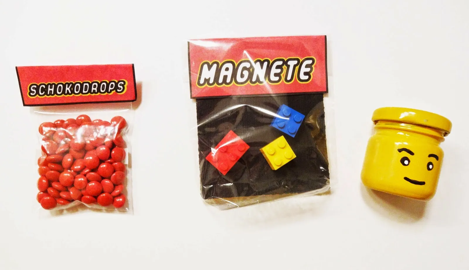 Verschiedene LEGO-Gastgeschenke: Magnete, Gläser mit Minifiguren und Schokolade