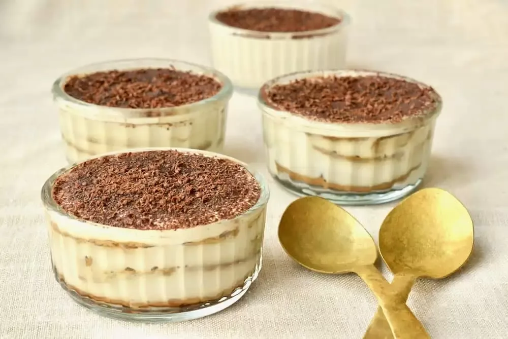 Vier kleine Auflaufförmchen gefüllt mit leckerem veganen Tiramisu