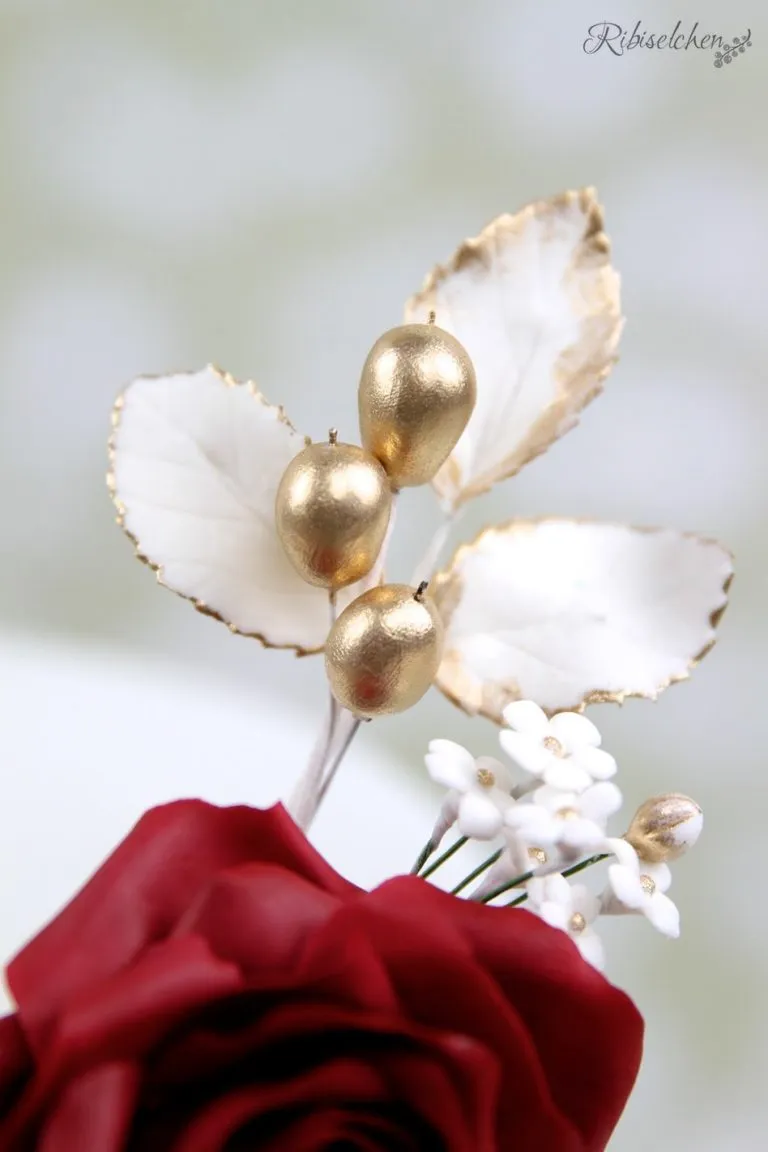 Weiße Zuckerrosen und goldene Beeren als Tortendekoration