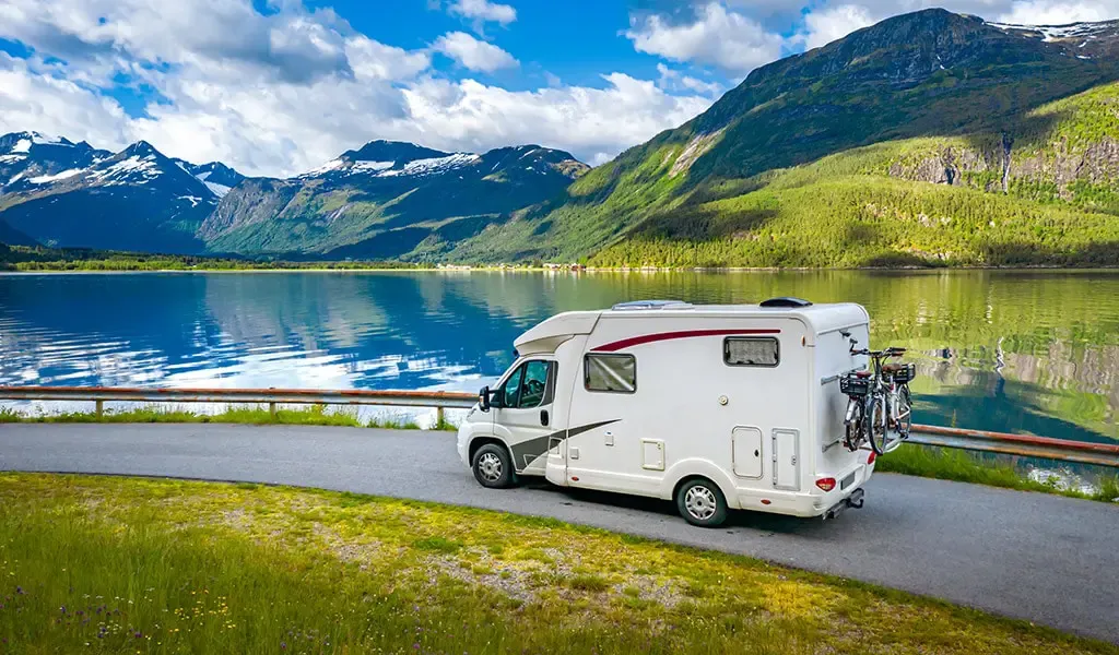 Wohnmobil vor traumhafter Kulisse mit Bergen und See.