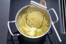 Zerstampfen der Kartoffelmasse mit einem Kartoffelstampfer