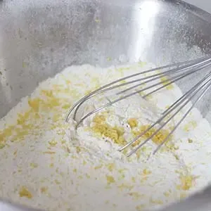 Zitronenschale und Zucker zu den trockenen Zutaten geben