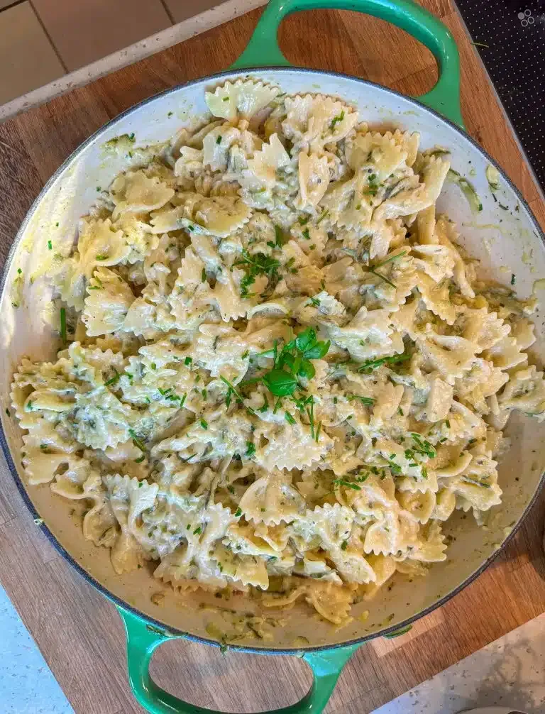 Zucchini Pasta wird in einer Pfanne mit Soße und frischem Basilikum zubereitet