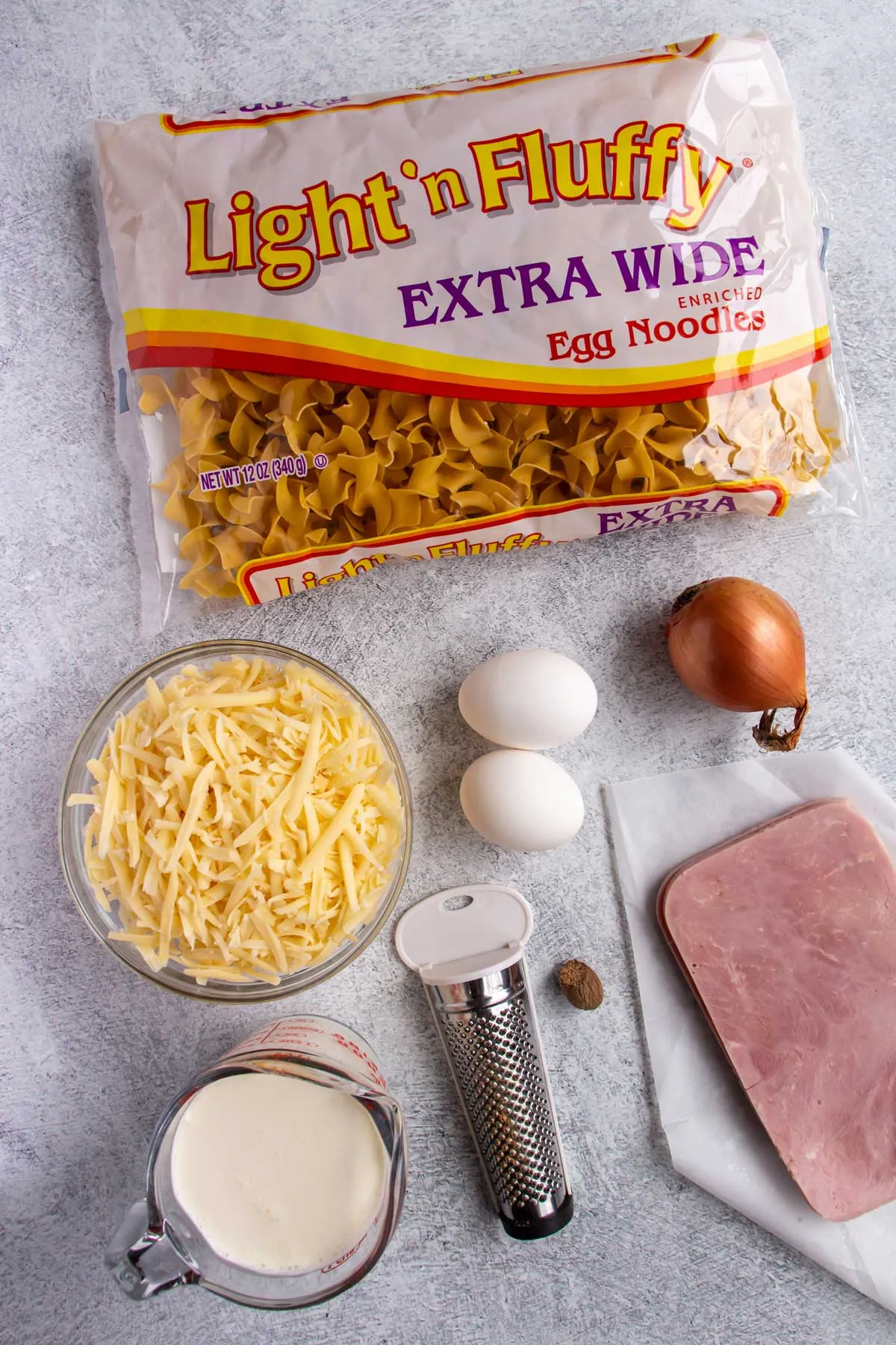 Zutaten für Schinkennudeln, deutscher Schinken-Nudel-Auflauf, auf grauem Betonhintergrund