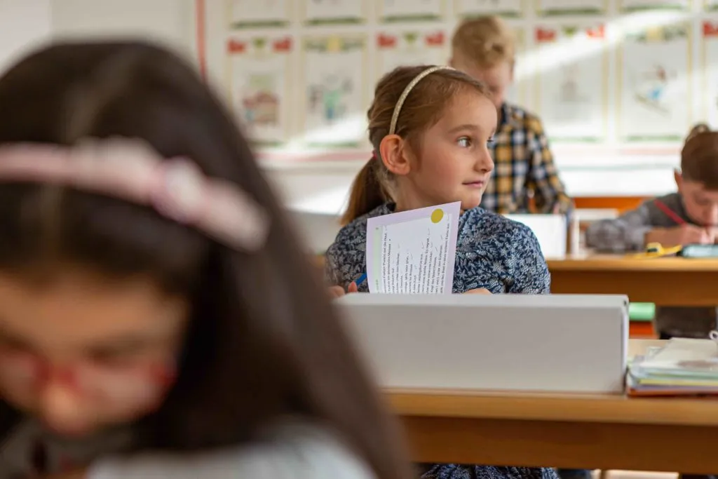 Zwei Kinder sitzen an einem Tisch und lernen in einer hellen Umgebung