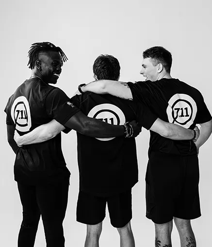 Zwei Personaltrainer umarmen einen neuen Mitglied im Fitnessstudio